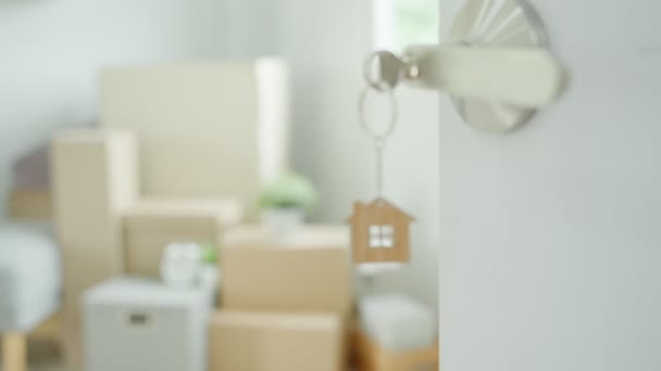 钥匙插在新房子的门上 房间里有一个装有个人物品和家具的纸板箱 搬进公寓或公寓 — 图库视频影像