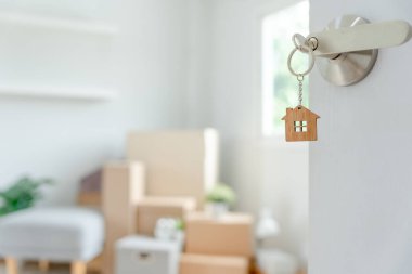 Moving house, relocation. The key was inserted into the door of the new house, inside the room was a cardboard box containing personal belongings and furniture. move in the apartment or condominiu