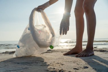 Su tasarrufu. Gönüllü olarak plajdaki çöpleri topluyor ve plastik şişeler suda yaşayan canlılara zarar gelmesini engelliyor. Dünya, Çevre, Yeşilci Gezegen, küresel ısınmayı azaltmak, Dünya 'yı kurtarmak