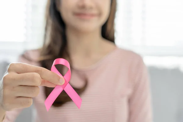 Woman hold pink ribbon breast cancer awareness. Female health check consciousness. international Women Day and World Cancer Day. sign cancer; Symbolic; health care; support patients; timely diagnosis