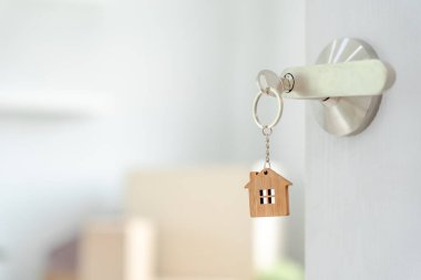 Moving house, relocation. The key was inserted into the door of the new house, inside the room was a cardboard box containing personal belongings and furniture. move in the apartment or condominiu