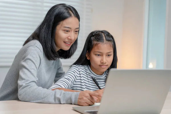 online tutor online course for Asian children. video conference on laptop at home. play back online course, girl student wear earphones to study, notes homework, video classes, new education.