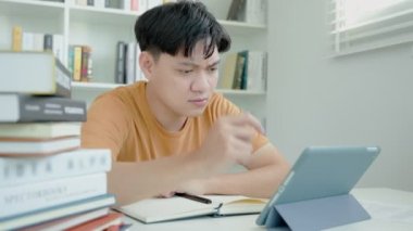 Asian student man research sample exam by tablet, male prepare for test and learning lessons in the library. stress, despair, haste, misunderstanding reading, discouraged, expectation, knowledge