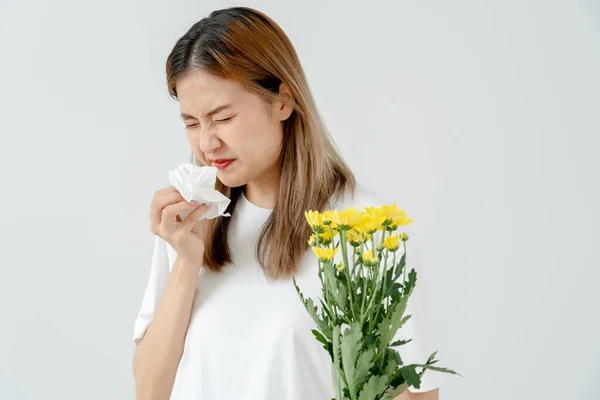 Pollen Allergies, young woman sneezing in a handkerchief or blowing in a wipe, allergic to wild spring flowers or blossoms during spring. allergic reaction, respiratory system problems, runny nose.