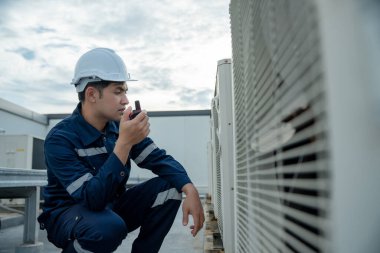 Asian maintenance engineer work on the roof of factory. contractor inspect compressor system and plans installation of air condition systems in construction. technology, walky talky, maintenance
