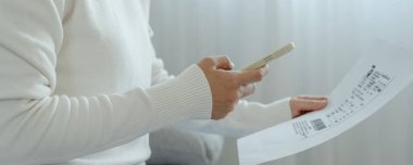 Kadın, belge faturasını aldıktan sonra kredi kartı faturasını ödemek için telefon tarama barkodu ya da QR kodları kullanıyor. ödeme, ödeme, ödeme, dijital ödemeler, teknoloji, tarama, mali işlemler