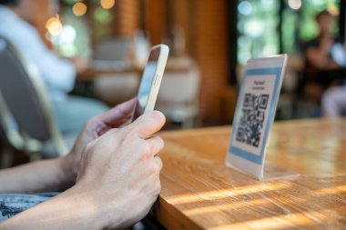 Woman use smartphone to scan QR code to pay in cafe restaurant with a digital payment without cash. Choose menu and order accumulate discount. E wallet, technology, pay online, credit card, bank app.
