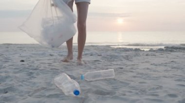 Su tasarrufu. Gönüllü olarak plajdaki çöpleri topluyor ve plastik şişeler suda yaşayan canlılara zarar gelmesini engelliyor. Dünya, Çevre, Yeşilci Gezegen, küresel ısınmayı azaltmak, Dünya 'yı kurtarmak