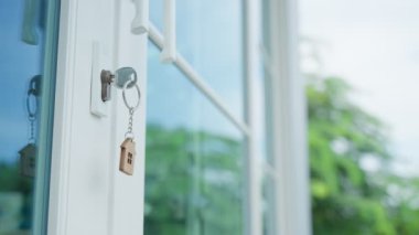 Landlord key for unlocking house is plugged into the door. Second hand house for rent and sale. keychain is blowing in the wind. mortgage for new home, buy, sell, renovate, investment, owner, estate