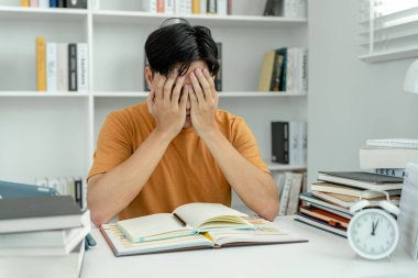 Asian student man have anxiety because of exams, male prepare for test and learning lessons in the library. stress, despair, haste, misunderstanding reading, discouraged, expectation, knowledge