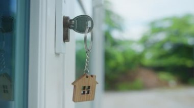 Landlord key for unlocking house is plugged into the door. Second hand house for rent and sale. keychain is blowing in the wind. mortgage for new home, buy, sell, renovate, investment, owner, estate