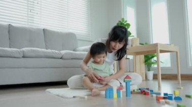 Mutlu Asya anneleri küçük kızla oynar ve oyuncak blokları öğrenir. Komik aile evde mutlu ve heyecanlı. Anne ve kızı birlikte vakit geçiriyorlar. Tatil, Etkinlik, Geliştirme
