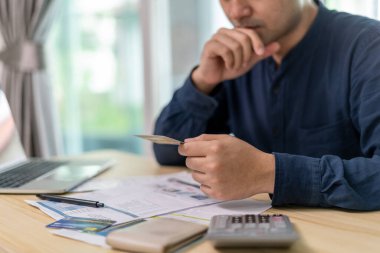 Yüklü faturaları ve faturaları olan stresli ve baş ağrısı çeken Asyalı bir adamın harcamaları ve kredi kartı borçlarını ödeyecek parası yok. kıtlık, mali sorunlar, mortgage, kredi, iflas, iflas, yoksul, boş cüzdan