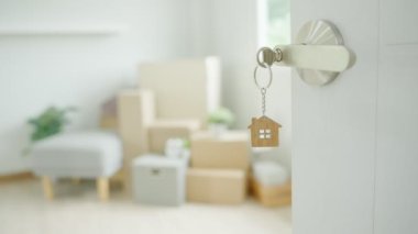 Moving house, relocation. The key was inserted into the door of the new house, inside the room was a cardboard box containing personal belongings and furniture. move in the apartment or condominium