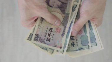 Japon Yen parası. Japon yenini elinizin altında tutun. Japonya 'nın değişim, alım, satım, birikim, yatırım, finans, döviz kuru, değer, muhasebe, uluslararası döviz kurunda kullanılan para birimi