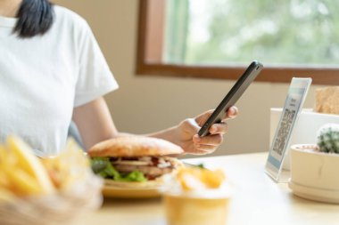 Woman use smartphone to scan QR code to pay in cafe restaurant with a digital payment without cash. Choose menu and order accumulate discount. E wallet, technology, pay online, credit card, bank app.