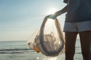 Su tasarrufu. Gönüllü olarak plajdaki çöpleri topluyor ve plastik şişeler suda yaşayan canlılara zarar gelmesini engelliyor. Dünya, Çevre, Yeşilci Gezegen, küresel ısınmayı azaltmak, Dünya 'yı kurtarmak