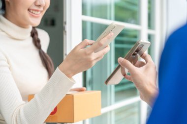 Mutlu bir gülümseme Asyalı kadın yemek parası için QR kodunu tarıyor. Teslimatçı ekspres teslimat gönderdi. Çevrimiçi dükkan, kağıt konteynır, paket servis, paket, elektronik para, dijital transfer