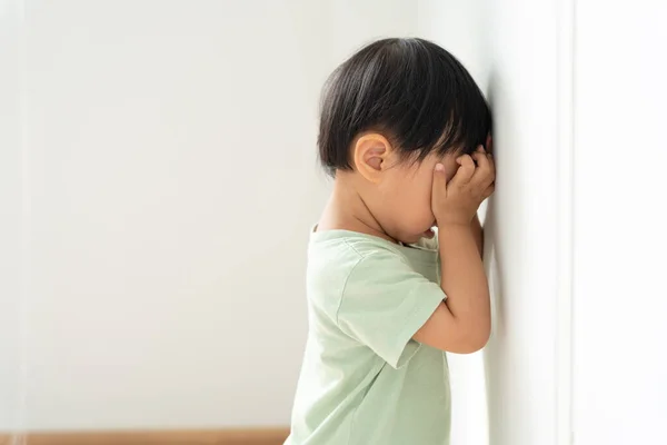 stock image little asian children kid girl covering his eyes with hands, playing hide and seek standing next a wall house, Adorable child having fun in the home. happy family have fun with kids, activity, learning