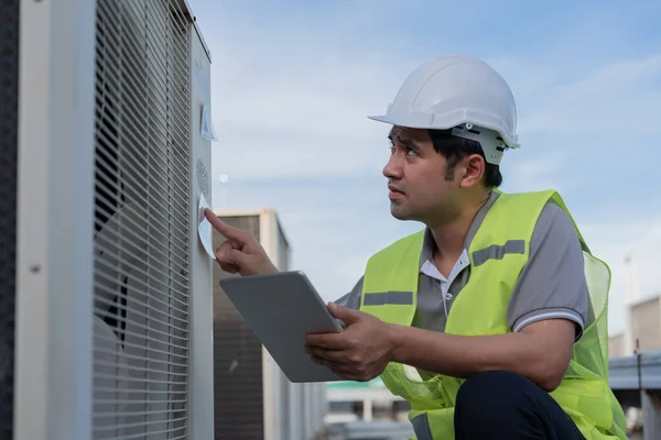 Asian maintenance engineer works on the roof of factory. contractor inspect compressor system and plans installation of air condition systems in construction. technology, online checking