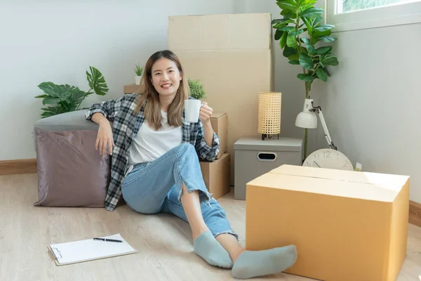 Moving house, relocation. Woman feel good and recreation on new apartment, inside the room was a cardboard box containing personal belongings and furniture. move in the house or condominiu