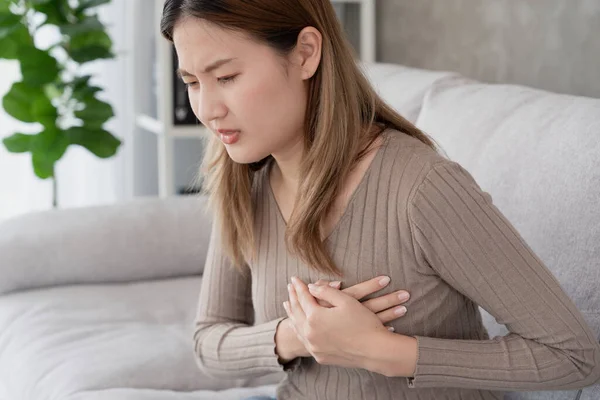 asian woman have chest pain caused by heart disease, leak, dilatation, enlarged coronary heart, press on the chest with a painful expression, heart attack, hand hold chest with heart attack symptoms