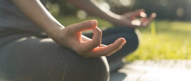 Kadın parkta meditasyon yapıyor. Sabahları egzersiz yapan Asyalı bir kadın. denge, dinlenme, rahatlama, sakinlik, sağlık, mutluluk, rahatlama, sağlıklı yaşam tarzı, stresi azaltma, huzur, tutum.