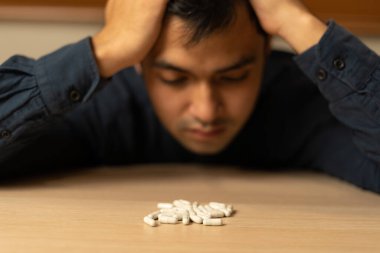 Asyalı erkek aşırı dozda hap kullanıyor, stresli, üzgün, uyuşturucu bağımlısı, uyuşturucu bağımlısı, hasta, sağlıksız, mutsuz, intihar, depresyonda veya umutsuz, uyuşturucu bağımlısı, yaşam ve aile sorunları, motivasyonsuz