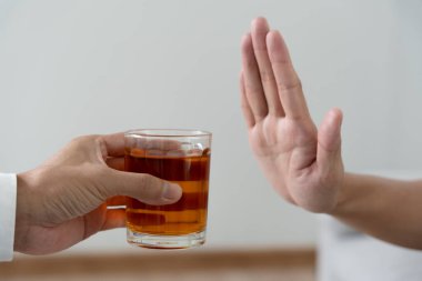 Adam hayır demeyi reddediyor ve alkollü viski içmekten kaçınıyor, el işareti yapan erkek, alkolizm tedavisi, alkol bağımlılığı, içkiyi bırakmak, alkol içmeyi bırakmak. İçkiyi reddet, sağlıksız, reddedilmiş
