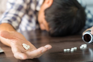 Asyalı erkek aşırı dozda hap kullanıyor, stresli, üzgün, uyuşturucu bağımlısı, uyuşturucu bağımlısı, hasta, sağlıksız, mutsuz, intihar, depresyonda veya umutsuz, uyuşturucu bağımlısı, yaşam ve aile sorunları, motivasyonsuz