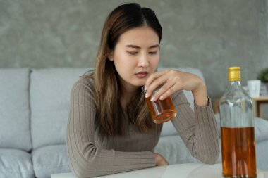 Depresyondaki genç Asyalı kadın evde yalnız başına viski içmenin kötü hissettirdiğini vurguladı alkol içmek sorunlu içki, alkolizm, hayat ve aile sorunlarından muzdarip.