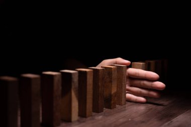 Domino 'yu elleri olan sigorta korur. İş adamı elleri iş krizinde domino taşlarının düşmesini durdurur. işletme risk denetimi ve planlama ve işletmeler sigorta işletmelerini önlemek için stratejiler.