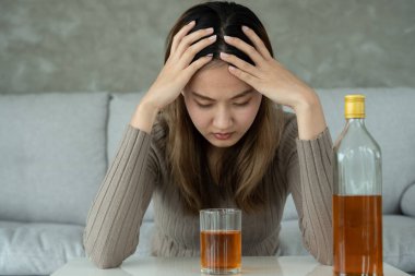 Depresyondaki genç Asyalı kadın evde yalnız başına viski içmenin kötü hissettirdiğini vurguladı alkol içmek sorunlu içki, alkolizm, hayat ve aile sorunlarından muzdarip.