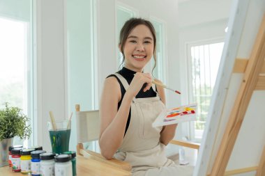beautiful female hobbies about artist and use paintbrush in abstract art for create masterpiece. painter paint with watercolors or oil in studio house. enjoy painting as hobby, recreation, inspiration