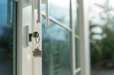 Landlord key for unlocking house is plugged into the door. Second hand house for rent and sale. keychain is blowing in the wind. mortgage for new home, buy, sell, renovate, investment, owner, estate