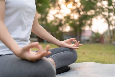 Kadın parkta meditasyon yapıyor. Sabahları egzersiz yapan Asyalı bir kadın. denge, dinlenme, rahatlama, sakinlik, sağlık, mutluluk, rahatlama, sağlıklı yaşam tarzı, stresi azaltma, huzur, tutum.
