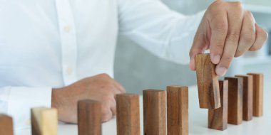 Domino 'yu elleri olan sigorta korur. İş adamı elleri iş krizinde domino taşlarının düşmesini durdurur. işletme risk denetimi ve planlama ve işletmeler sigorta işletmelerini önlemek için stratejiler.