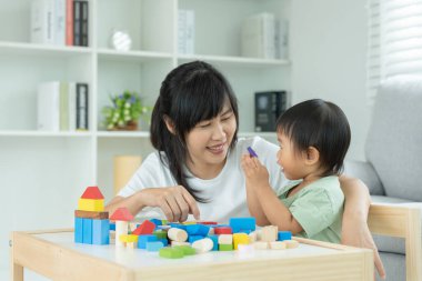 Mutlu Asya anneleri küçük kızla oynar ve oyuncak blokları öğrenir. Komik aile evde mutlu ve heyecanlı. Anne ve kızı birlikte vakit geçiriyorlar. Tatil, Etkinlik, Geliştirme