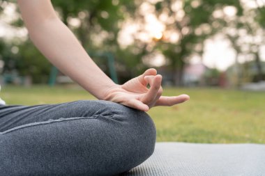 Kadın parkta meditasyon yapıyor. Sabahları egzersiz yapan Asyalı bir kadın. denge, dinlenme, rahatlama, sakinlik, sağlık, mutluluk, rahatlama, sağlıklı yaşam tarzı, stresi azaltma, huzur, tutum.