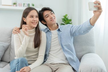 Asian couples are enjoying new home and taking selfies together. Teenage husband and wife after marriage. Happiness and smiles and laughter in warm family. cuddling, warm hugs, teenager's first love