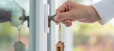 Moving house, relocation. Woman hold key house keychain in new house. move in new home. Buy or rent real estate. flat tenancy, leasehold property, new landlord, dwelling, loan, mortgage.