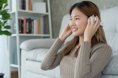 Asyalı güzel kız mutlu bir şekilde gülümsüyor. Müzik dinlemek, dinlenmek, hobiler, tatilde iyi hissetmek. genç bayan başarısı, reklam panosu, tanıtım, reklam, çekici, ifade, pozitif