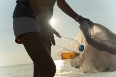 Su tasarrufu. Gönüllü olarak plajdaki çöpleri topluyor ve plastik şişeler suda yaşayan canlılara zarar gelmesini engelliyor. Dünya, Çevre, Yeşilci Gezegen, küresel ısınmayı azaltmak, Dünya 'yı kurtarmak
