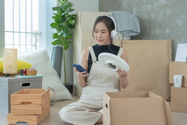 Moving house, relocation. asian woman feel good and recreation and enjoy music on new house, inside the room was a cardboard box containing personal belongings and furniture. move in  condominium