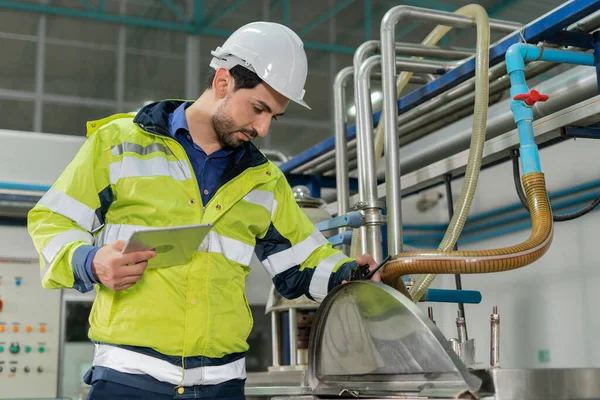 Güvenlik kaskı takan mühendisler veya fabrika yöneticileri üretim hattındaki makineleri inceler. Kamu müfettişi makineyi kontrol et ve standardı karşılamak için sistemi test et. makine, bakım.