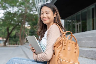 Beautiful student asian woman with backpack and books outdoor. Smile girl happy carrying a lot of book in college campus. Portrait female on international Asia University. Education, study, schoo