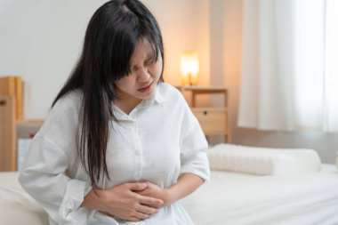 stomach ache. Asian women have abdominal pain, indigestion, gastritis, menstrual cramps, flatulence, diarrhea, distention, colon cancer, belly inflammation problem, suffer food poisoning, abdomen