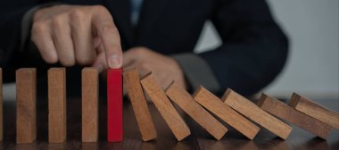 Domino 'yu elleri olan sigorta korur. İş adamı elleri iş krizinde domino taşlarının düşmesini durdurur. işletme risk denetimi ve planlama ve işletmeler sigorta işletmelerini önlemek için stratejiler.