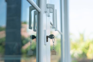 Landlord key for unlocking house is plugged into the door. Second hand house for rent and sale. keychain is blowing in the wind. mortgage for new home, buy, sell, renovate, investment, owner, estate