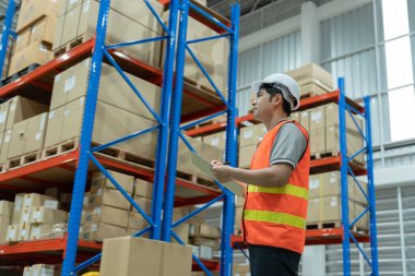 Depo çalışanı, envanterde ve stok ürünlerinde kutu ürünlerini kontrol ediyor. Lojistik ticaret nakliyat ve teslimat müşterilere, denetim, depo, depo, fabrika.